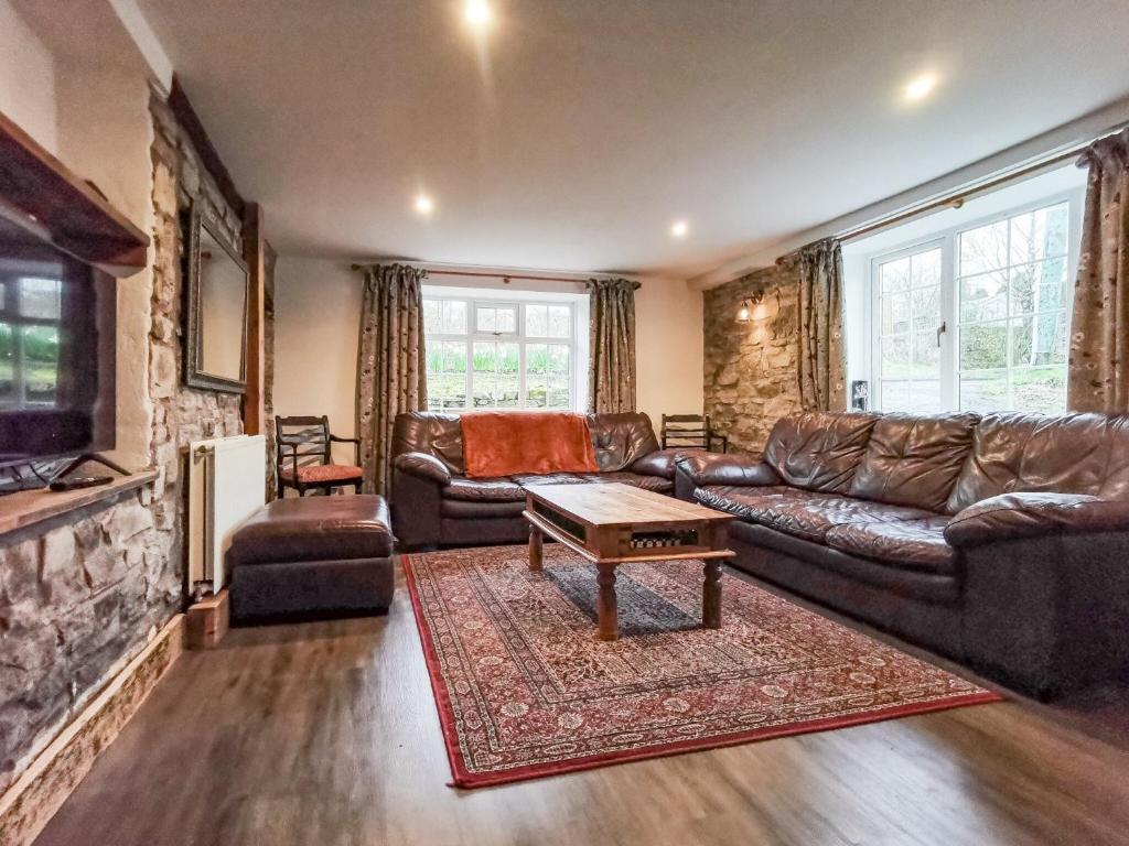 uma sala de estar com mobiliário de couro e uma parede de pedra em Daffodils em Coanwood
