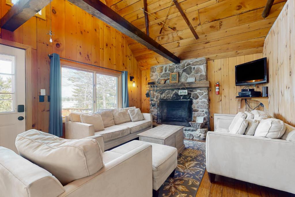 a living room with white furniture and a stone fireplace at Peace by Province Lake in Wakefield