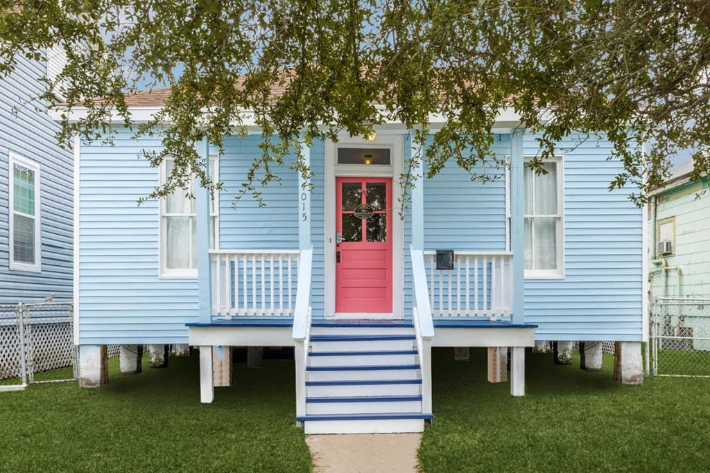 a blue house with a red door and stairs at Cozy sea breeze bungalow - 2 mins to the beach in Galveston