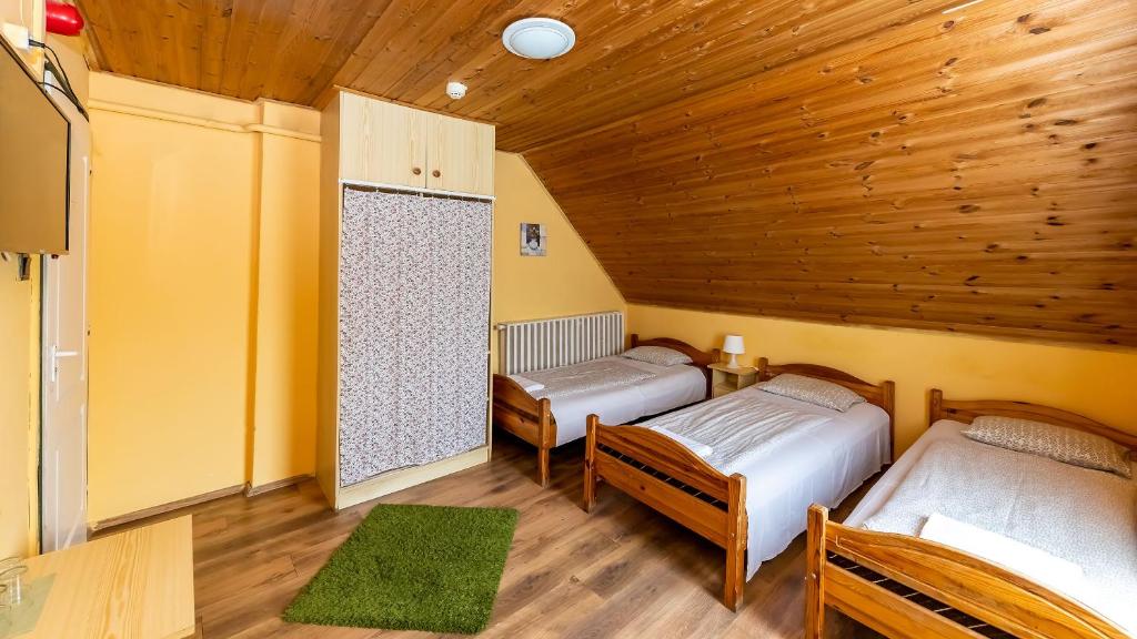 two beds in a room with a wooden ceiling at Csillagtúra Panzió in Eger