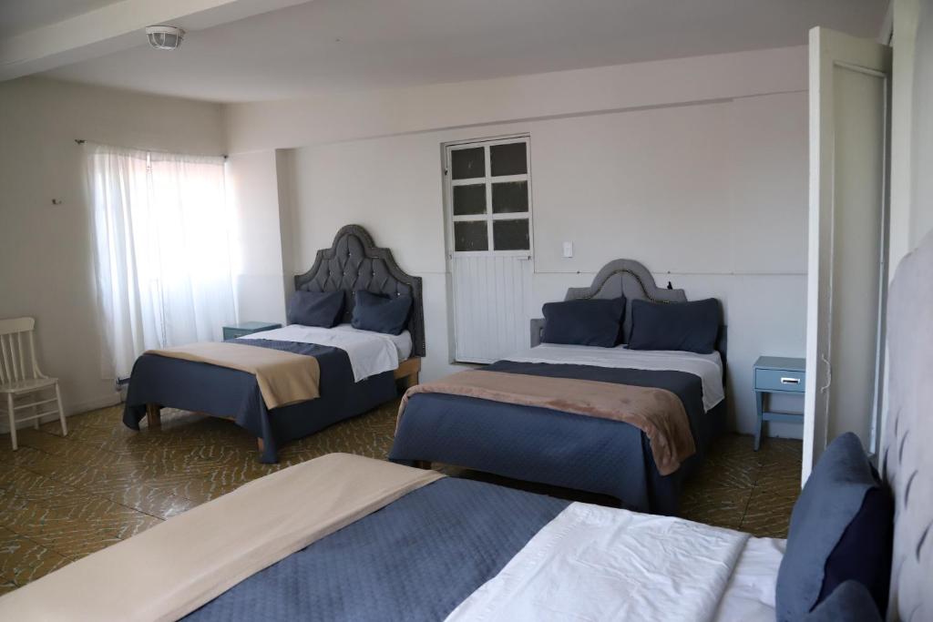 a hotel room with two beds and two chairs at Hotel El Rincón de Jesusita in Durango