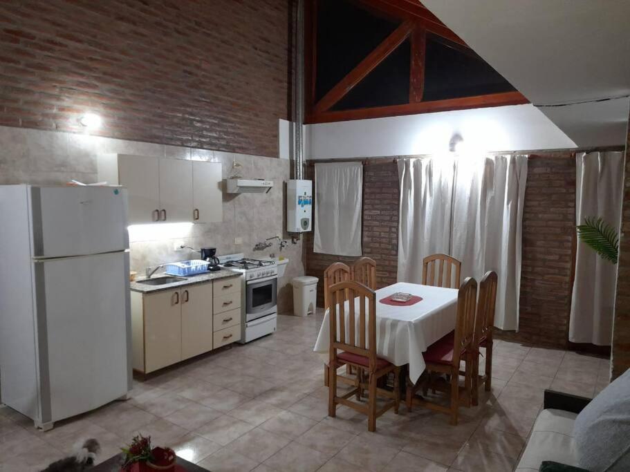 eine Küche mit einem Tisch und einem weißen Kühlschrank in der Unterkunft Departamento Centrico in Villa General Belgrano