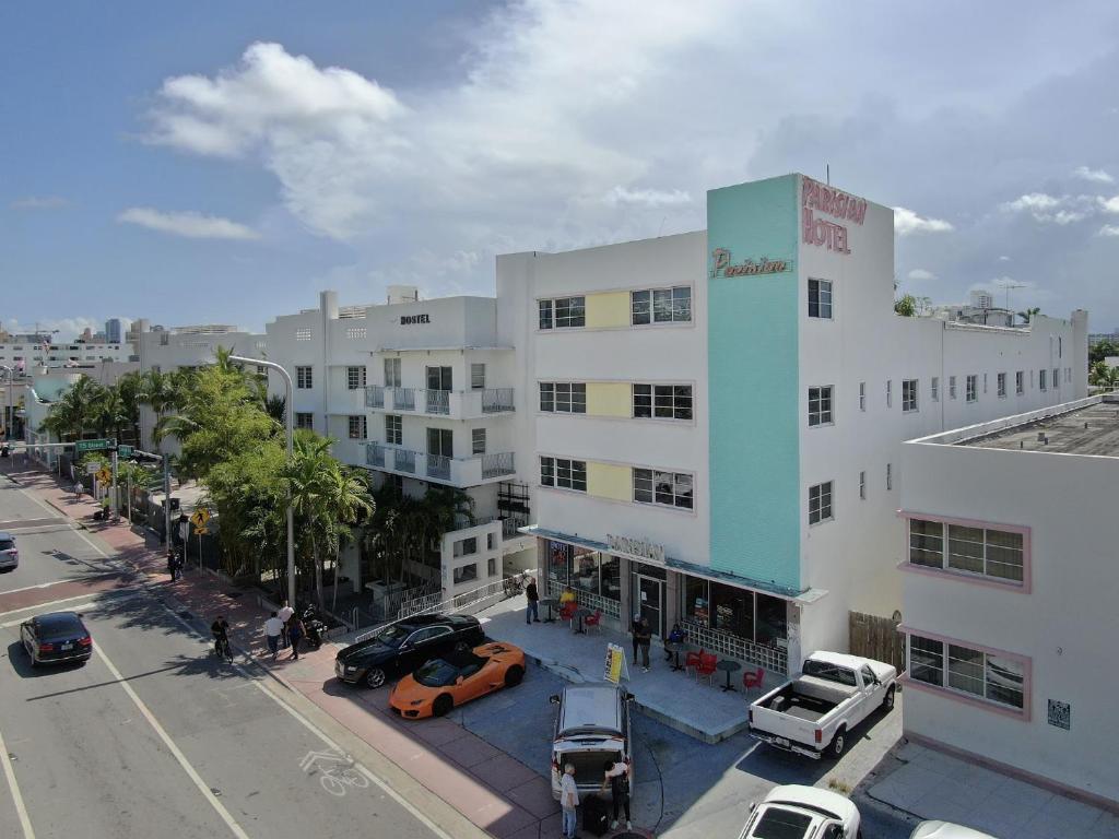 un gran edificio blanco con coches estacionados frente a él en Parisian Hotel, en Miami Beach
