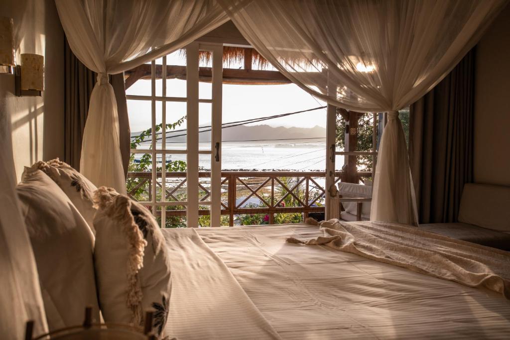 a bedroom with a bed with a view of the ocean at Serenity Luxurious Beachfront Villa & Spa with private Infinity Pool, 8 Guests in Gili Air