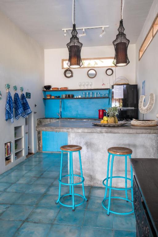 a kitchen with blue cabinets and two stools at Serenity Luxurious Beachfront Villa & Spa with private Infinity Pool, 8 Guests in Gili Air