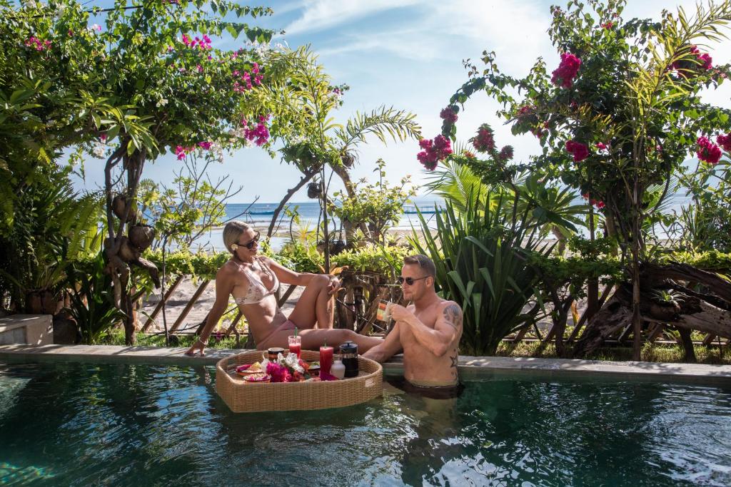 two people sitting in a swimming pool at a resort at Serenity Luxurious Beachfront Villa & Spa with private Infinity Pool, 8 Guests in Gili Air