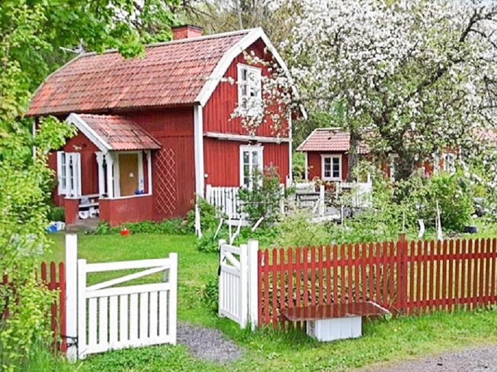 una casa roja con una valla blanca delante de ella en Holiday home Österhaninge, en Västerhaninge