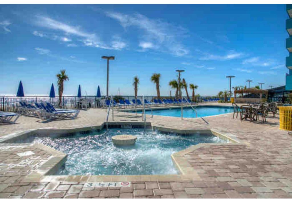 una piscina en un complejo con palmeras y sillas en Upgraded Studio at Landmark Resort ! 17 pools, lazy rivers, jacuzzis! 814 en Myrtle Beach