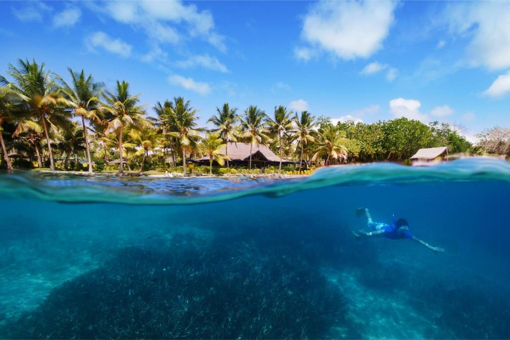 a person swimming in the ocean in front of a resort at Aore Island Resort in Luganville