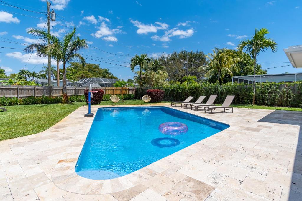 uma piscina num quintal com duas espreguiçadeiras em Hollywood Paradise Luxury 4BR 3BA Home and Outdoor Fun with Heated Pool em Hollywood