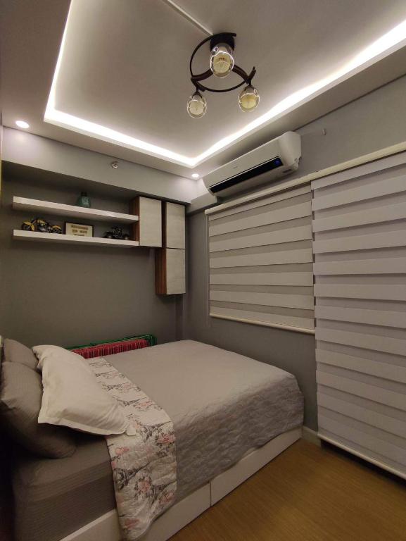 um quarto com uma cama num quarto com persianas em Maicozy condo em Manila