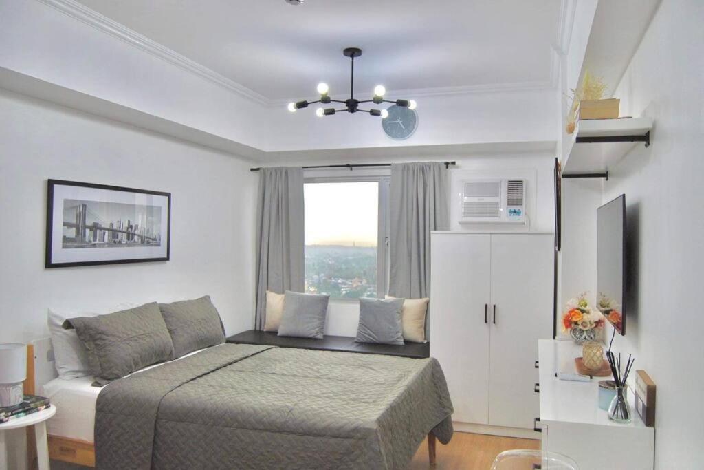 1 dormitorio con cama y ventana en New York Suite III at Avida Towers Aspira, en Cagayan de Oro