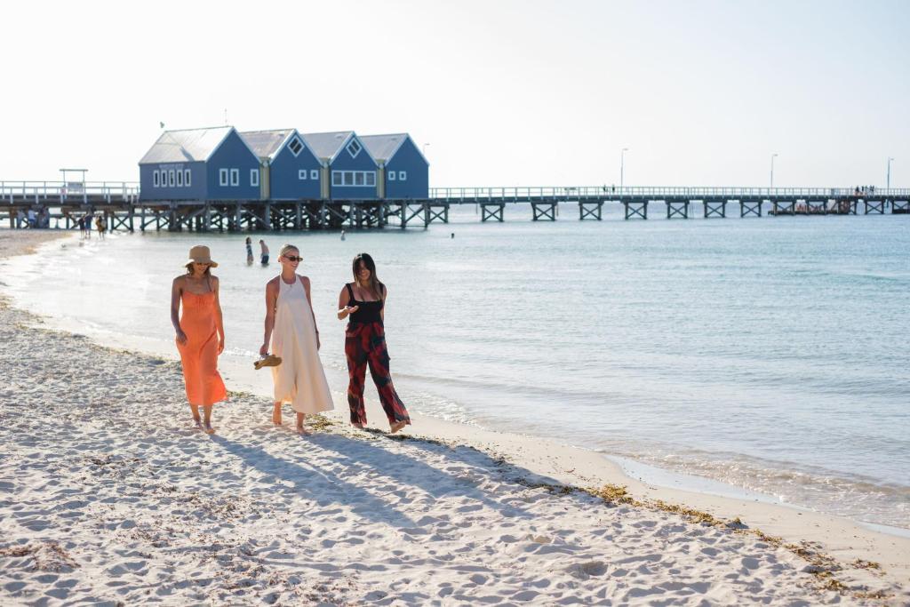 3 Leute laufen am Strand in der Nähe des Wassers in der Unterkunft Bayview Geographe Resort Busselton in Busselton