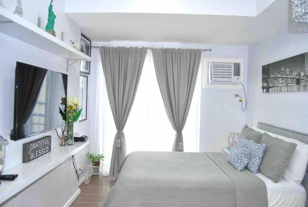 a white bedroom with a bed and a window at New York Suite at The Loop at Limketkai in Cagayan de Oro