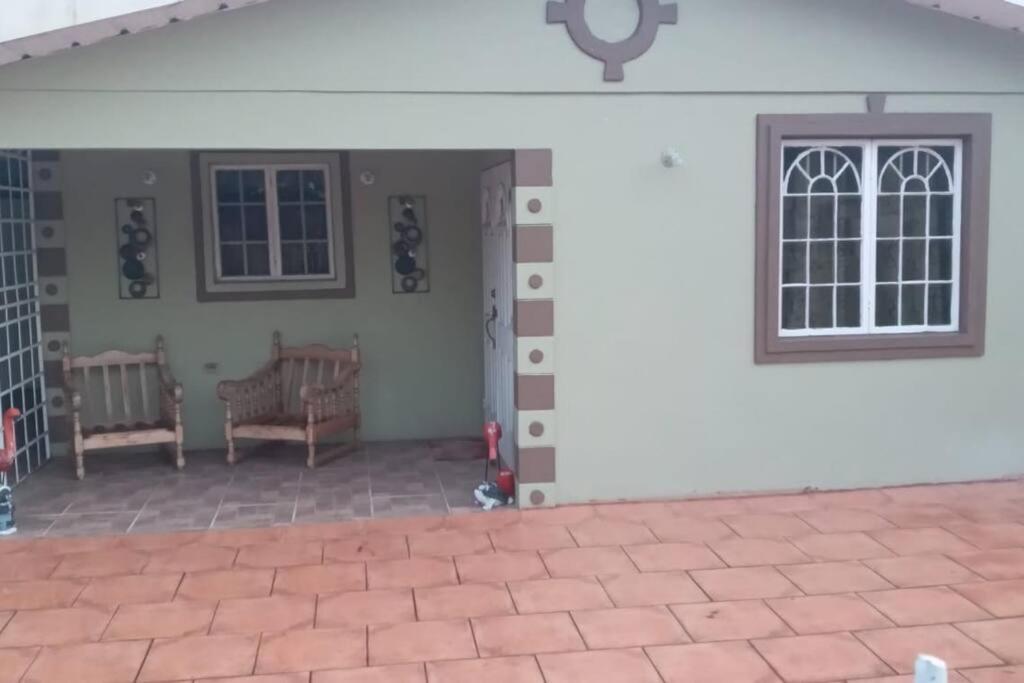 une terrasse couverte à l'avant d'une maison avec une horloge sur le mur dans l'établissement Spacious Home, à Couva