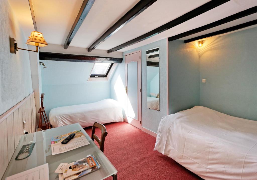 a small room with two beds and a table with a table sidx sidx at Cit'Hotel Hôtel Beauséjour in Cherbourg en Cotentin
