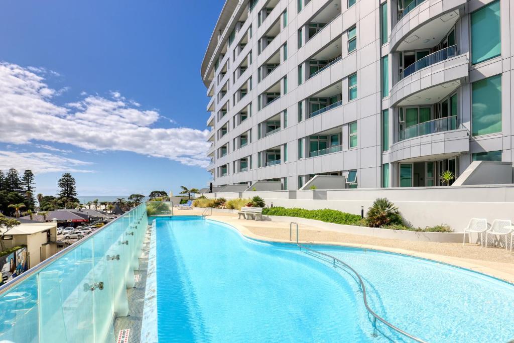 a swimming pool in front of a building at Ramada Suites by Wyndham Nautilus Orewa in Orewa