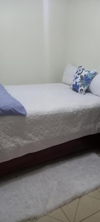 Una cama con sábanas blancas y almohadas azules. en Aparta Estudio Rubí. en San Felipe de Puerto Plata
