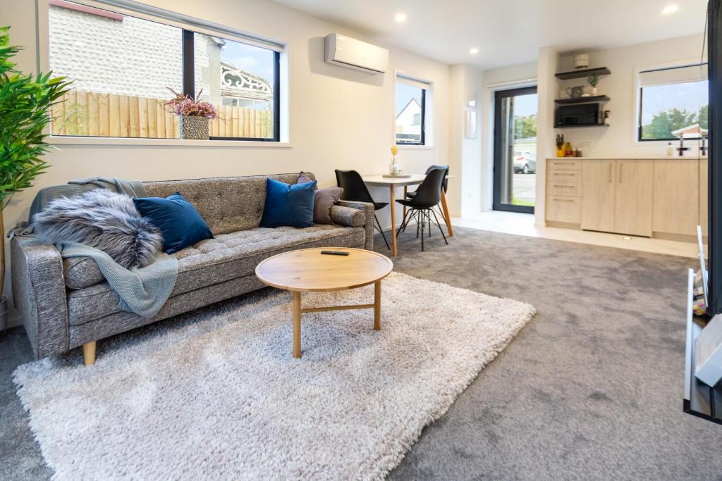 uma sala de estar com um sofá e uma mesa em Explore Addington and CBD 1 bed w/carpark em Christchurch