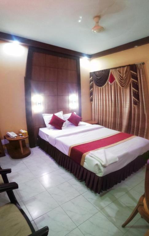 a hotel room with a large bed with red pillows at Hotel Skylink in Dhaka