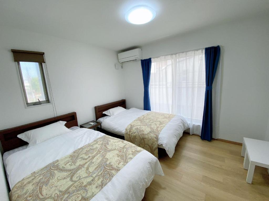 a bedroom with two beds and a window at ALL TRUST2馆临近心斋桥道頓堀难波直达梅田关西机场Usj全新独栋别墅四个卧室可住8人超大空间3卫2浴厨房设施齐全电视冰箱洗衣机空调配置齐全免费停车4分钟步行至今宫站 in Osaka