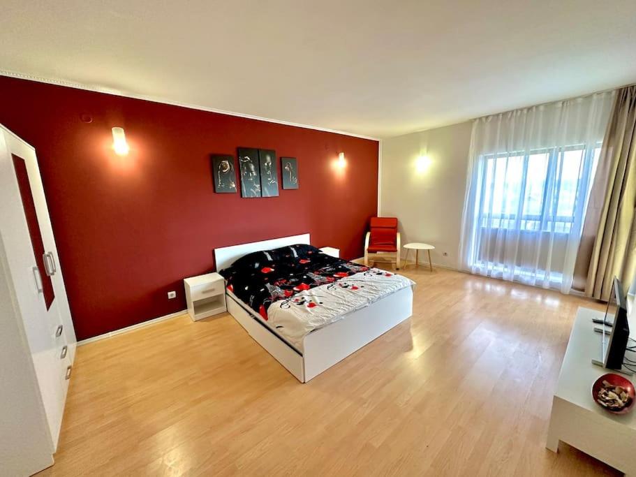 a bedroom with a bed and a red wall at Apartament Novara 2 in Craiova