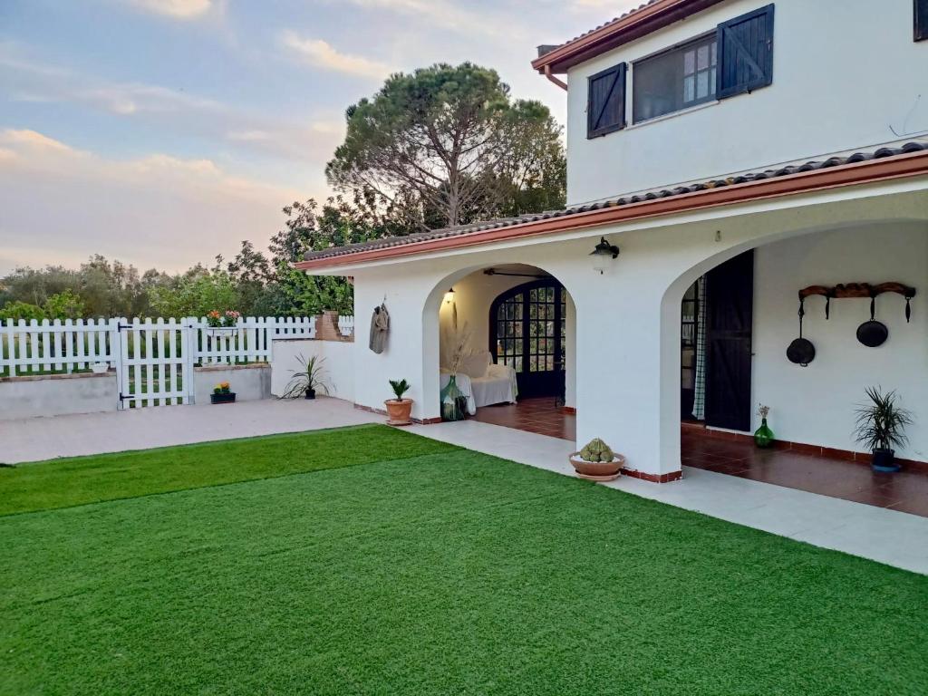 um quintal com uma cerca branca e relvado verde em Elvira Casa Vacanze em Iglesias