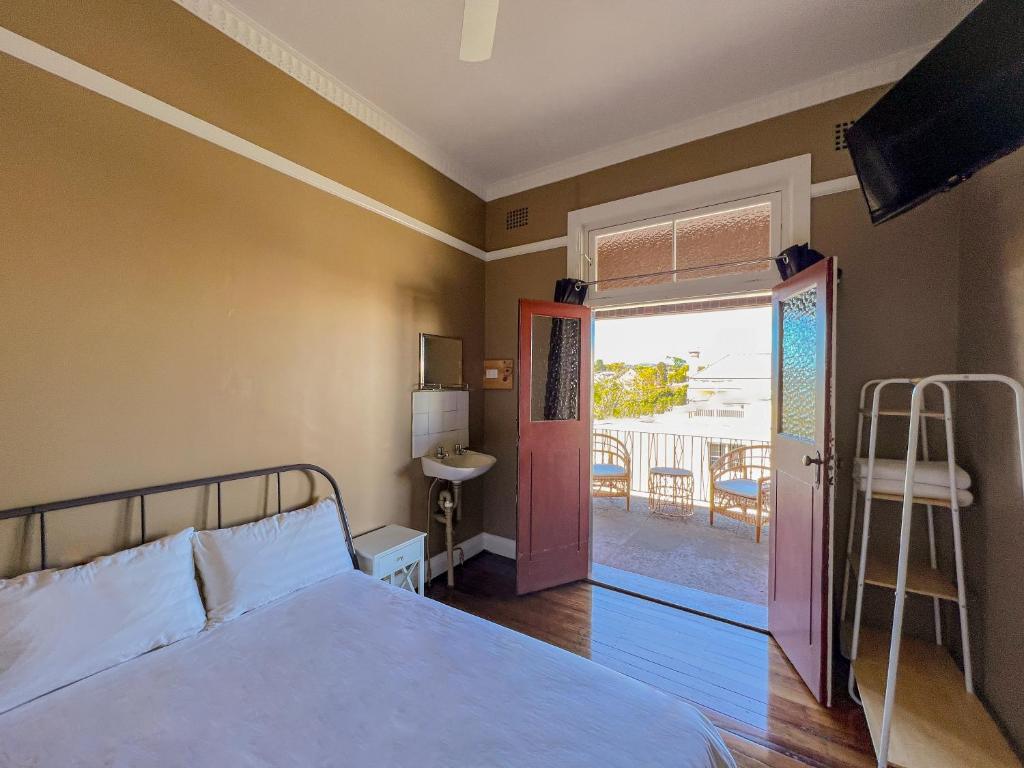 a bedroom with a bed and a door to a balcony at Commercial Hotel Bega in Bega