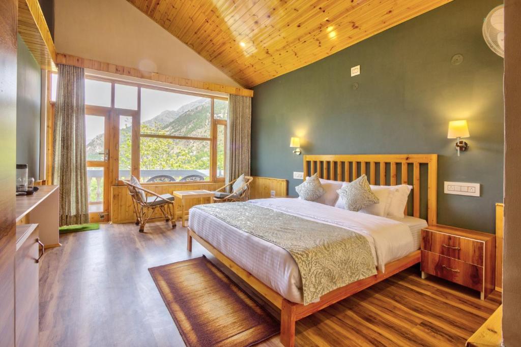 a bedroom with a large bed and a large window at Doris Mountain Cabins Tirthan in Banjār