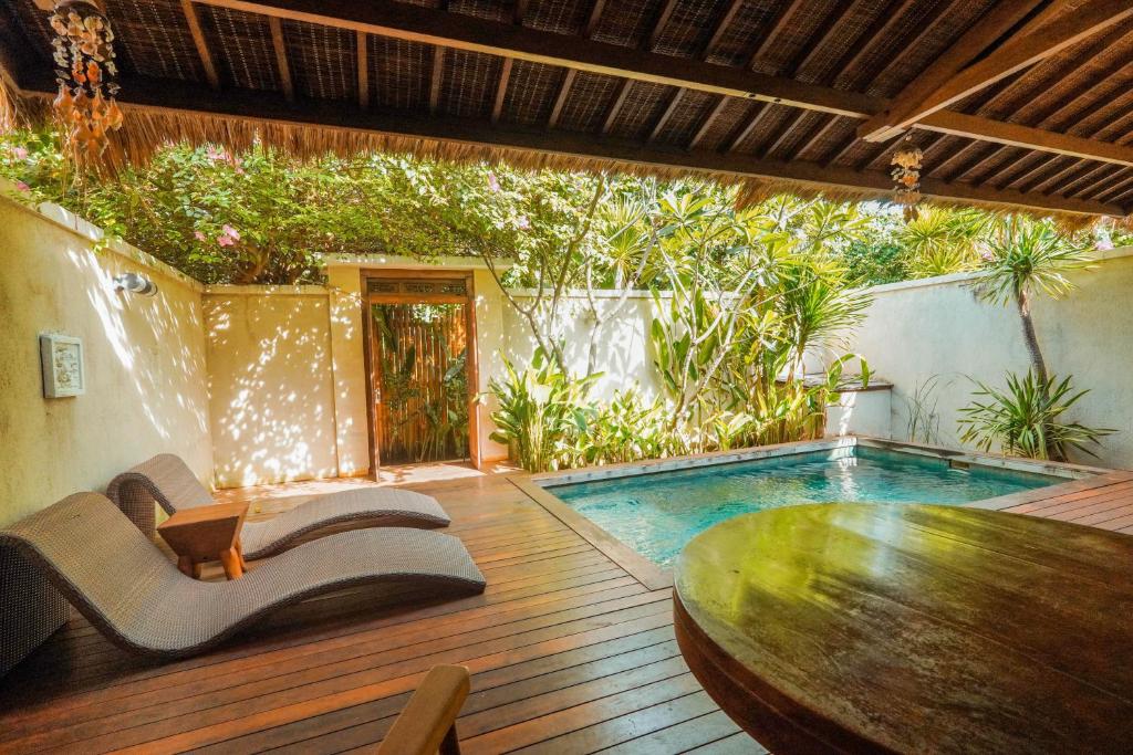 a patio with a table and a swimming pool at Pera ONE Villas in Gili Trawangan