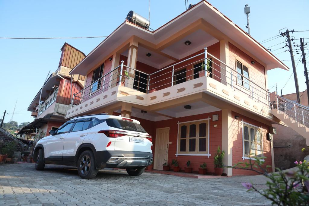 une voiture blanche garée devant une maison dans l'établissement Sai Home Stay, à Madikeri