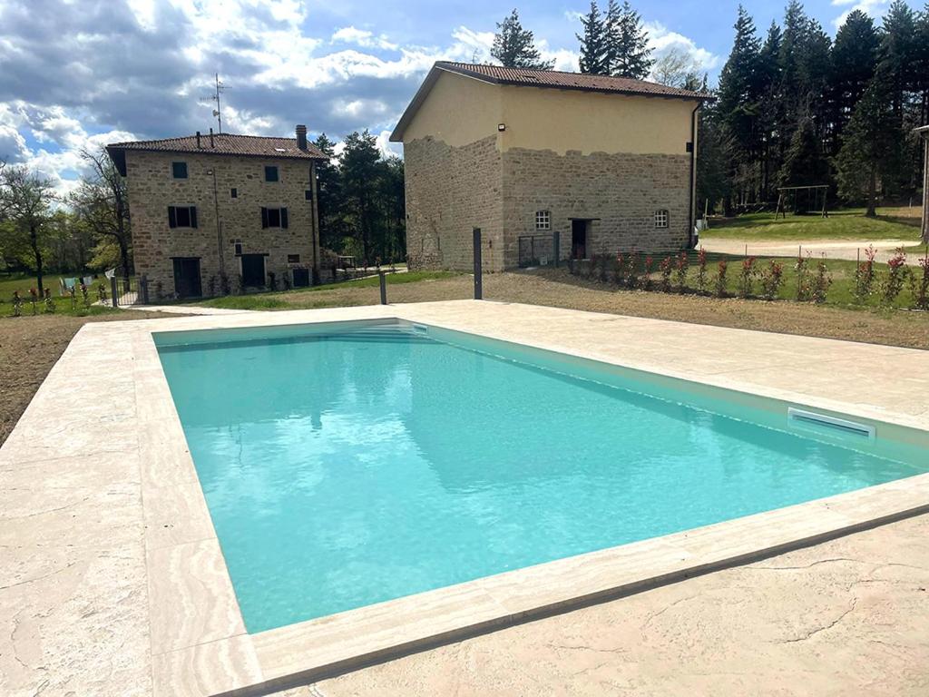 una grande piscina blu di fronte a un edificio di Agriturismo Il Casone a San Benedetto Val di Sambro