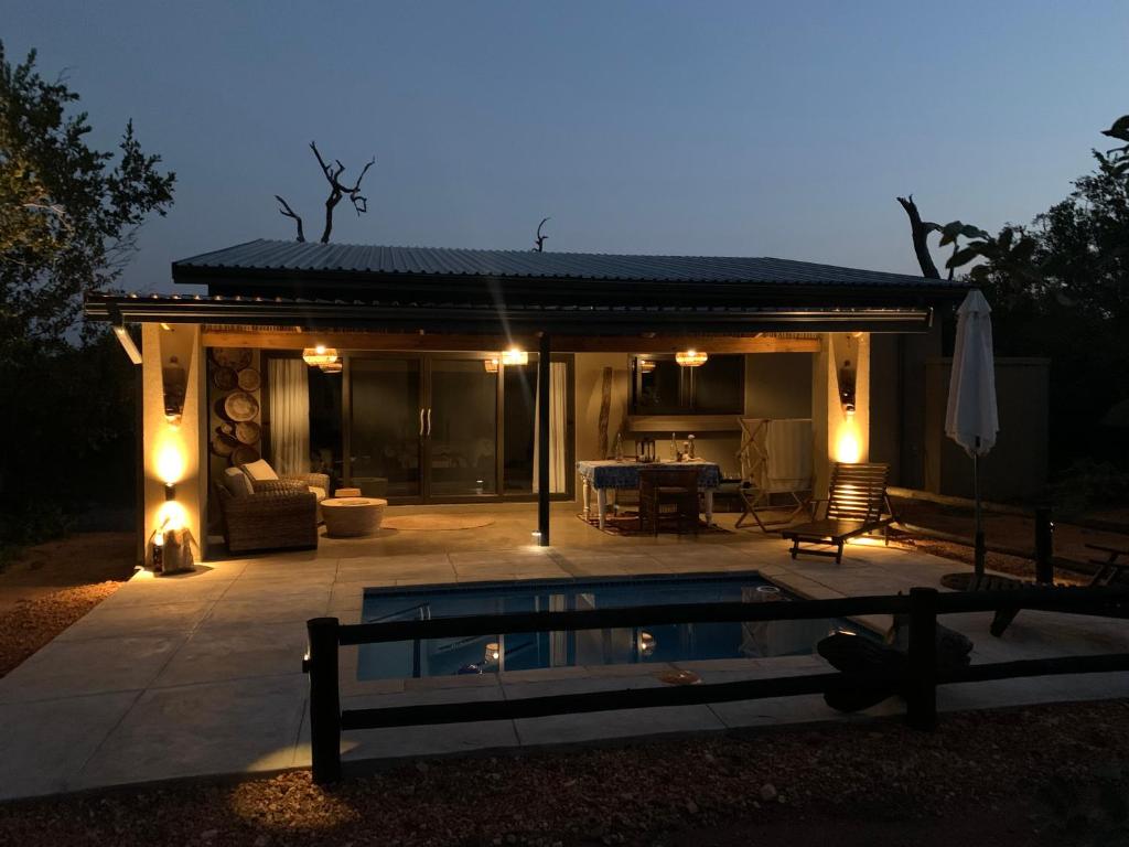 un patio con piscina frente a una casa en Rooibos Luxury Bush Cottage en Hoedspruit