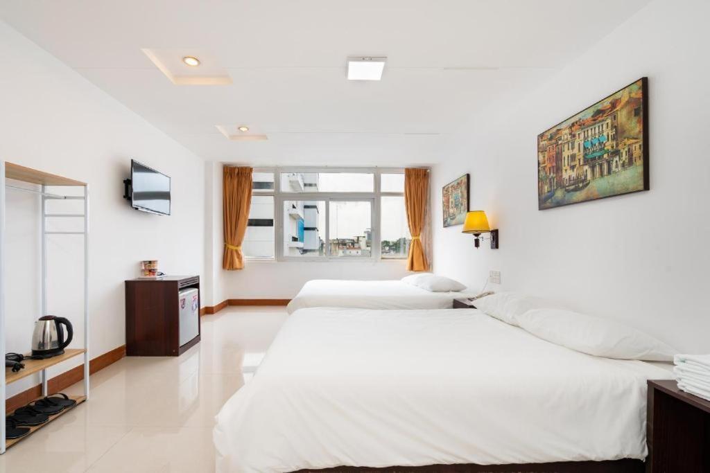 Duas camas num quarto branco com uma televisão. em Cabana Hotel - 47A Nguyen Trai, Q1 - by Bay Luxury em Ho Chi Minh