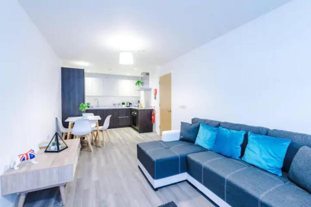 a living room with a blue couch and a kitchen at Spacious 2-Bedroom Apartment in the Heart of Manchester - Ideal for Families or Groups in Manchester