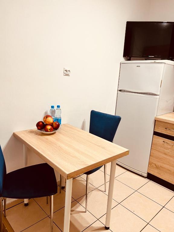 uma cozinha com uma mesa com uma tigela de frutas e um frigorífico em A4 Apartament II em Szczytnica