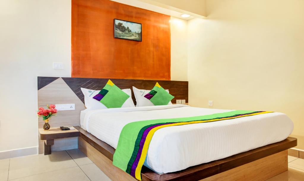 a bedroom with a large white bed with colorful pillows at Treebo Trend Golden Inn 700 Mtrs From Promenade Beach in Pondicherry