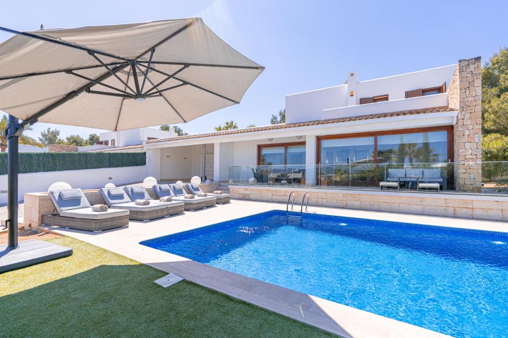 a villa with a swimming pool and an umbrella at Beautiful Villa Bohemia Ibiza in Sant Josep de sa Talaia