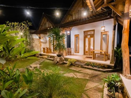 una pequeña casa con un jardín frente a ella en KUBU YANG COTTAGE, en Nusa Penida