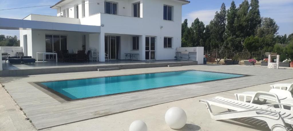 a villa with a swimming pool in front of a house at Kiti Village Villa Larnaca, salt-water pool, 5 bedrooms in Kiti