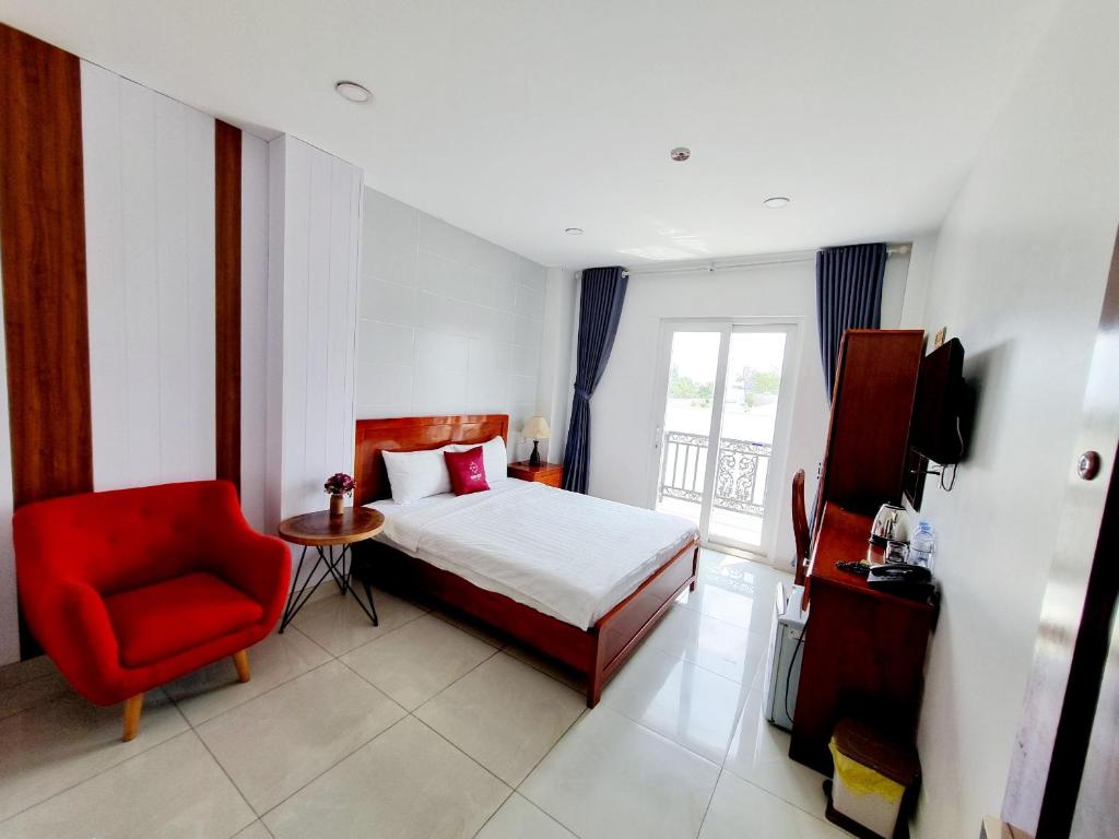 a bedroom with a bed and a red chair at Minh Khue Hotel in Vĩnh Long
