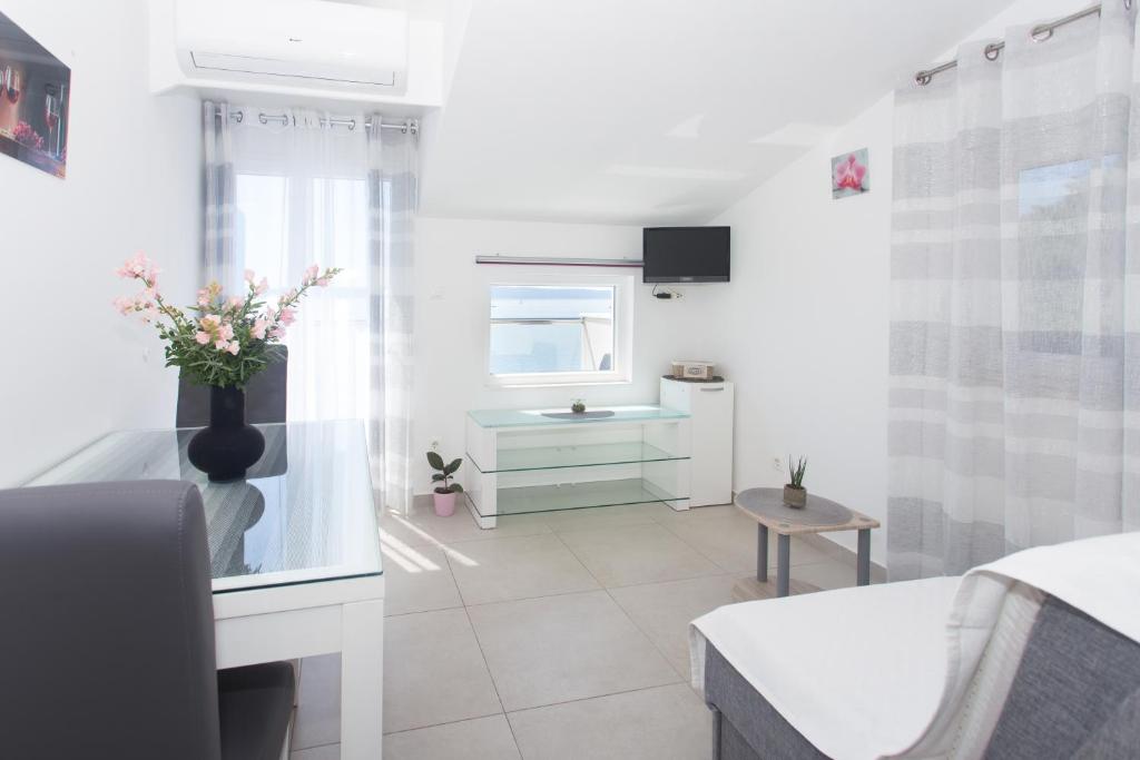 un soggiorno bianco con un vaso con fiori di Apartments Bandić - 30 meters to the beach a Trogir