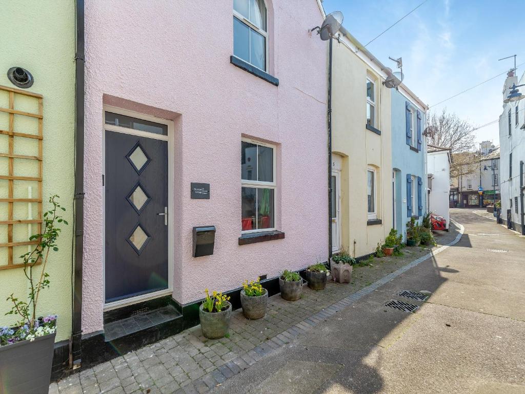 a pink house with potted plants on a street at Primrose Cottage in Teignmouth
