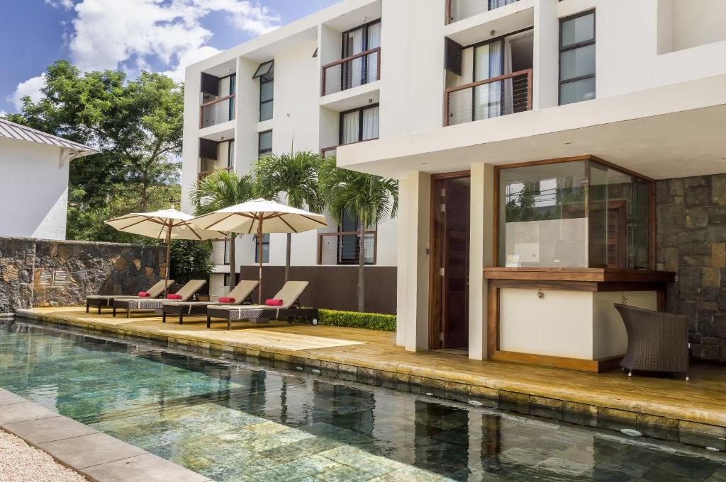 a swimming pool with chairs and umbrellas next to a building at Belle Haven Luxury Apartments in Mont Choisy