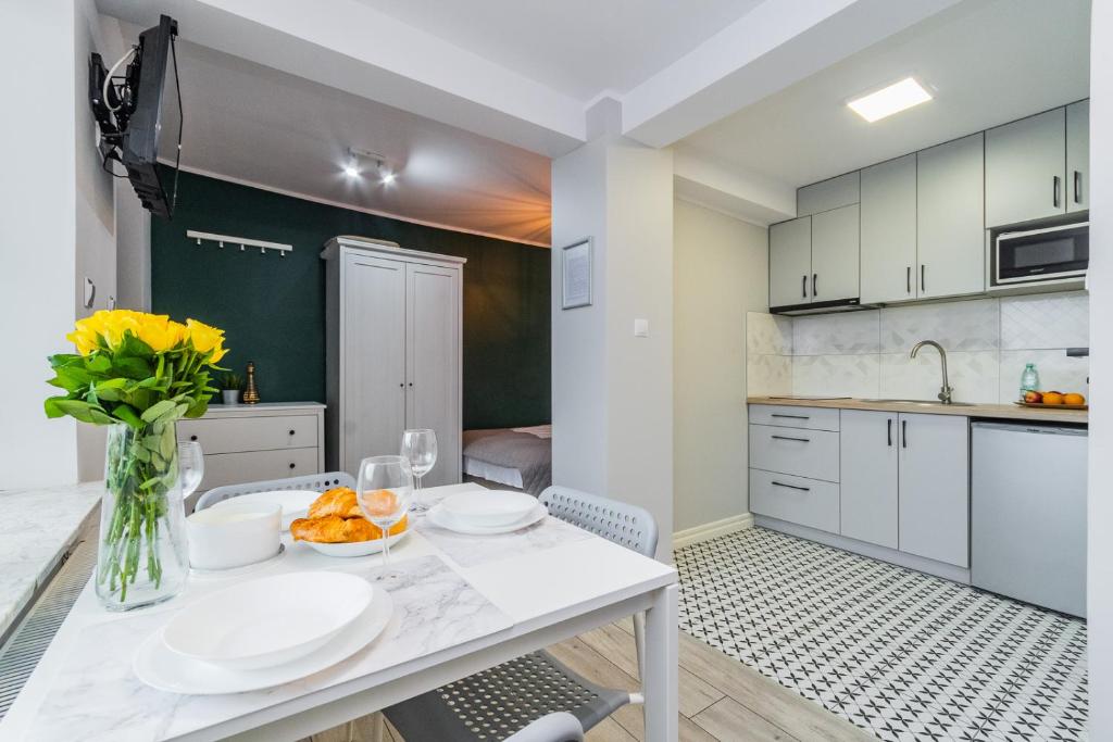 a kitchen with a table with plates and flowers on it at Apartamenty Cztery Kąty w Kątach Rybackich in Kąty Rybackie