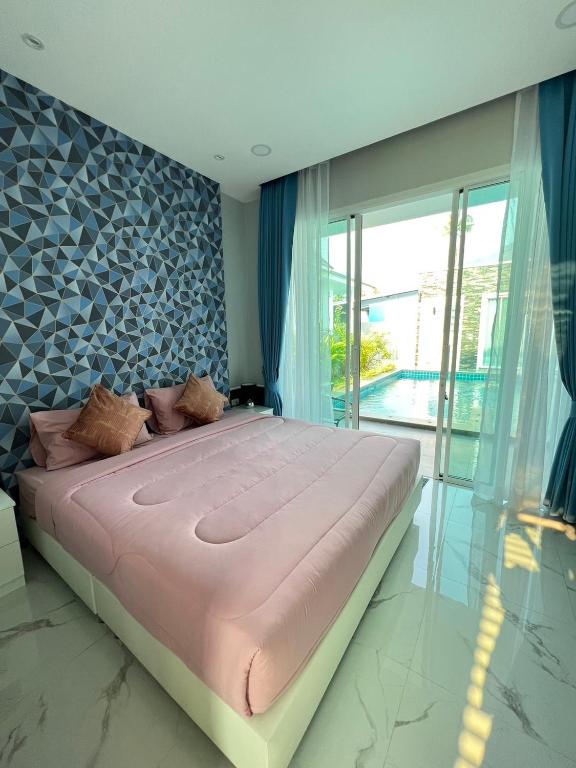 a bedroom with a large bed with a large window at Aranya pool villa in Ban Phu Yai