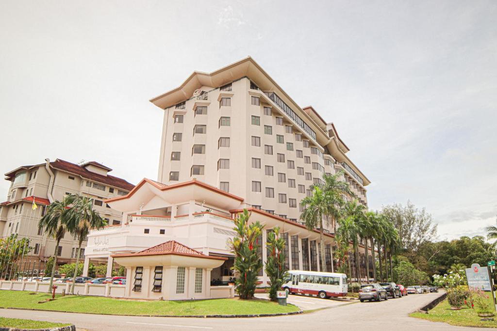 un edificio blanco alto con palmeras frente a una calle en Mulia Hotel, en Bandar Seri Begawan