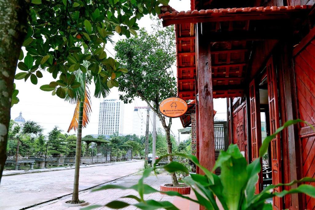 Ninh Binh Green Homestay في Ða Gia: مبنى احمر فيه اشجار على جانب شارع