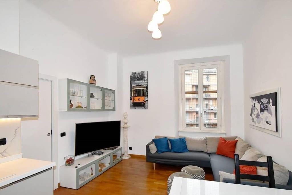 uma sala de estar com um sofá e uma televisão em Trilocale Centrale - Buenos Vibes em Milão