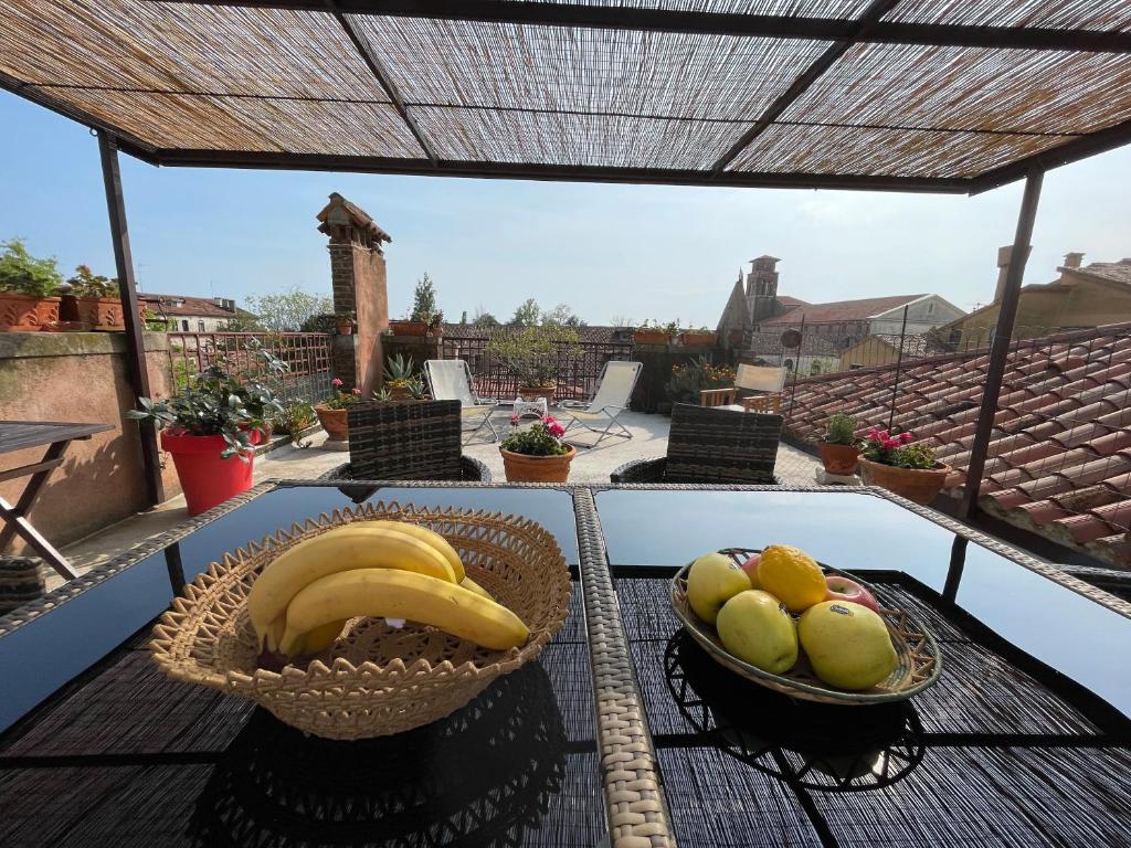 eine Schüssel mit Bananen und Äpfeln auf einem Tisch auf einem Balkon in der Unterkunft Giudecca Palanca 664 in Venedig